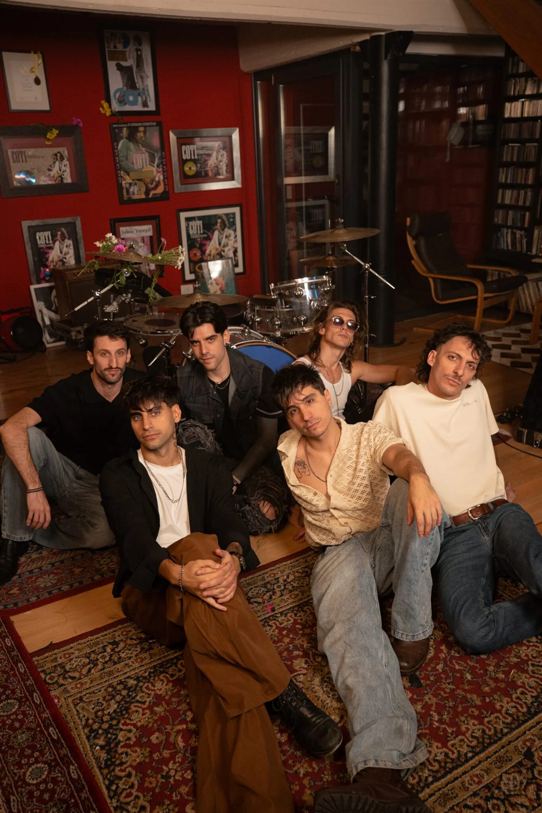 Los integrantes de Un Verano sentados en el piso de la sala de ensayo, entre la batería y los discos